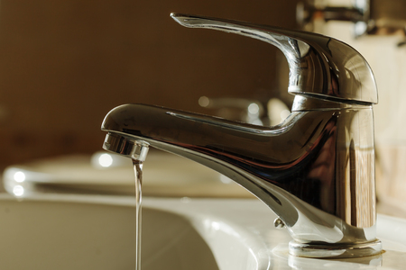 stream flows from a poorly closed faucet. Waste of waterの写真素材