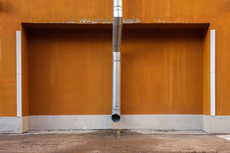 Downspout on a background of an orange wall