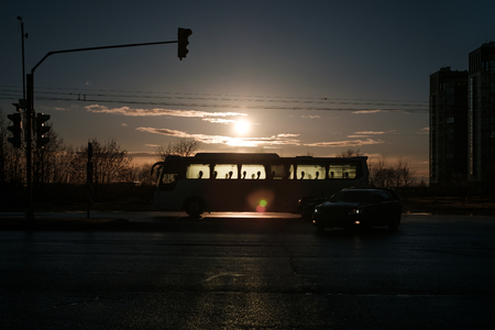 Silhouette of a city bus in the background of the setting sun.の写真素材