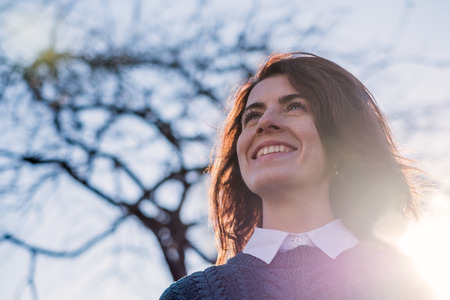 Red-haired girl smiles, enjoying the sun's rays.の写真素材