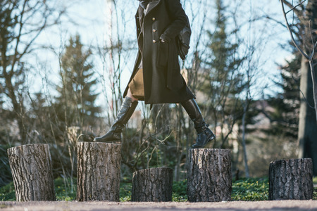 The girl in the forest steps over from the stump to the stump. Choose a difficult way to travelの写真素材