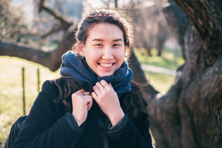 Portrait of an Asian happy girl. She looks at the camera and smiles, wrapped up in a scarf.