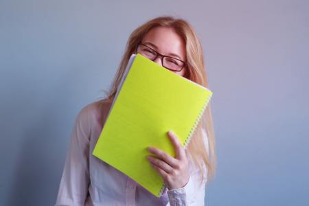 The girl secretary hides her face behind the papers. She is laughingの写真素材