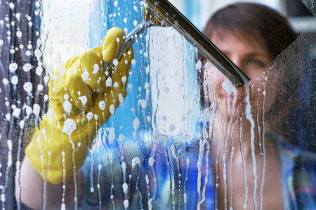 A girl washes windows at home. To clean up the house.の写真素材