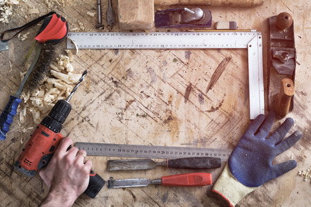 Back background for carpentry. Various tools for construction. Man holding a drillの写真素材