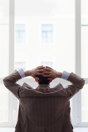 Portrait of a man in a suit by the window. Snapshot from the backの写真素材