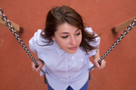 Happy excited teen girl on a chain swing, summer park outdoorの写真素材