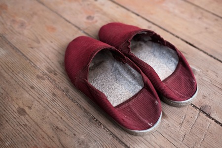 Warm red slippers on the background of old wooden floor.の写真素材