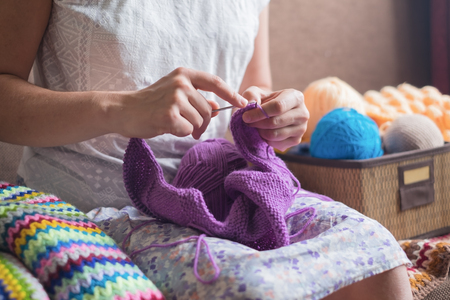 Caucasian woman knits woolen clothes. Holding knitting needles at handsの写真素材