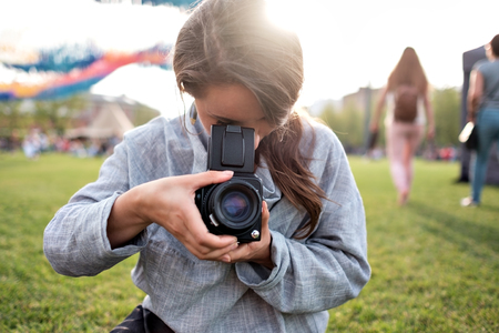 Pretty caucasian female using film photocamera. Traveling woman taking photo on vintage camera outdoor in summerの写真素材