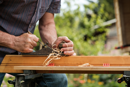 Man hands with carpenters plane on wooden background