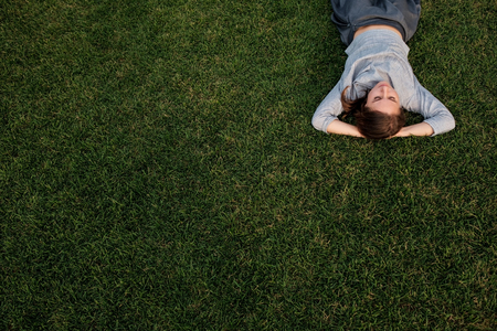 Beautiful young european woman lays down on grass and restsの写真素材