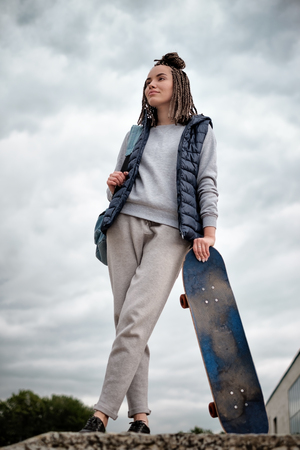 Beautiful hipster girl with skate board standing with smileの写真素材
