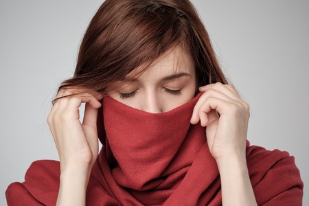 Portrait of red haired woman hiding face with scarf.の写真素材