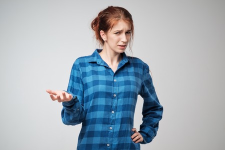 Portrait young angry woman in blue t-shirt. She is unhappy, annoyed by something.の写真素材