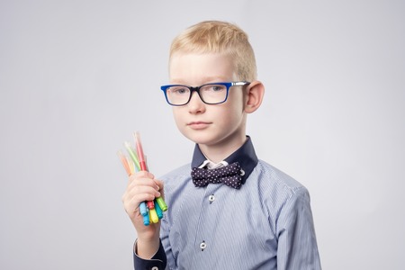 Caucasian boy with blond hair holding pencils in hands and looking upの写真素材