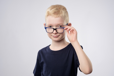 Cute caucasian blond boy holding glasses near eyesの写真素材