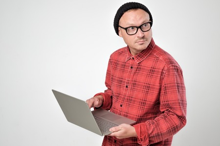 Caucasian man with laptop using remote control and looking aside.の写真素材