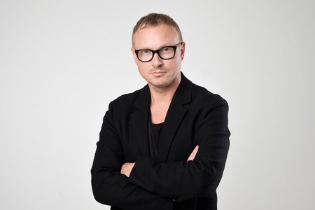 Smiling young man in black clothes standing against white backgroundの写真素材
