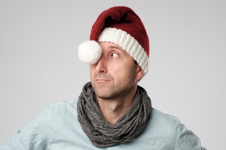 relaxed cauasian mature man wearing santa claus hat looking aside on grey backgroundの写真素材