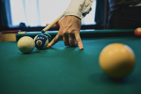 American billiard. Man playing billiard, snooker. Player preparing to shoot, hitting the cue ball.