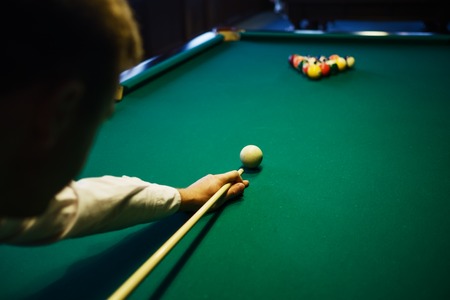 American billiard. Man playing billiard, snooker. Player preparing to shoot, hitting the cue ball.の写真素材