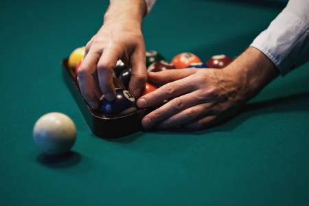 Playing billiard. Billiards balls on green billiards table. Caucasian player put ball inside. View from side. Billiard sport concept. Pool billiard game.の写真素材