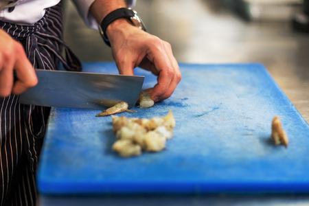 Chef is cutting raw shrimp with big special knife. Culinary seafood cooking.の写真素材