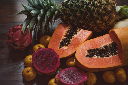 Juicy exotic fruits close up. Pineapple, papaya, mango, gragon fruit on table ready to eatの写真素材