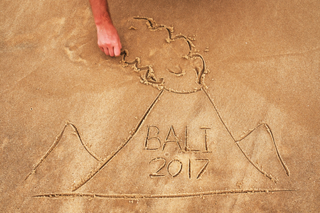 Picture on sand. Drawn volcano with text Bali inside. Dangerous cataclism in asiaの写真素材