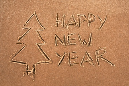 The inscription on the sand Happy New Year and Christmas tree. Postcard to the preparation of Christmas.の写真素材