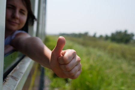 Young woman traveling by train in Thailand Asia. She shows thumb up
