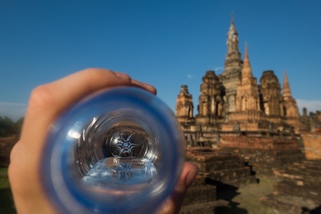 Man holding water bottle because he is thirsty and wants to drink. Thailand wat temple on backgroundの写真素材