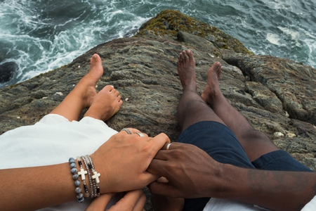 Top view on hands of just married couple. No face. They sit near ocean water during honeymoonの写真素材