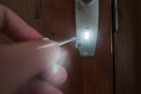 man hand opening door with key. Light is going out of door hole. Concept of safety or making choice.の写真素材