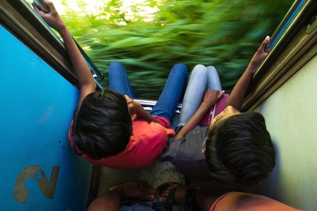 Ella, Sri Lanka 17 April 2018: Two teens riding on 2 class train and looking on nature