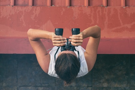 Caucasian woman in white shirt looking through the binoculars. Concept of active travel. Top viewの写真素材