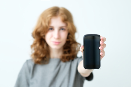 woman with red hairshow smart phone to you in the roomの写真素材