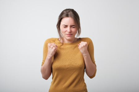 Young caucasian woman wishing for good luck. She is holding her fist and closing her eyesの写真素材