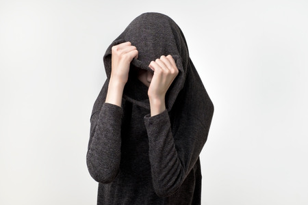 Woman hiding face under the clothes. She is oulling sweatr on her head. Depressed emotion. Wish to...