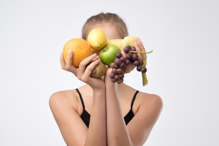 Young caucasian woman holding different fruits in hands. Diet healthy eating concept isolated on a white backgroundの写真素材