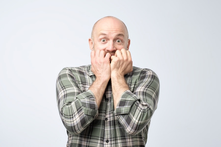 Closeup portrait of mature handsome man biting his finger nails He is afraid or anxious. Negative human emotion facial expression feelingの写真素材