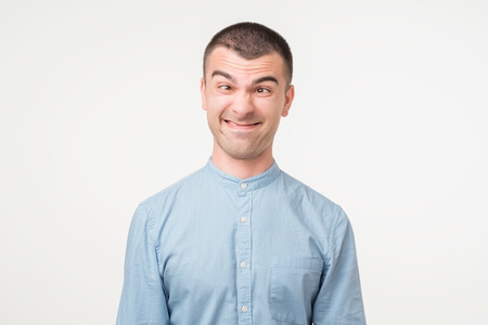 Caucaisan young man in blue shirt making silly face.の写真素材