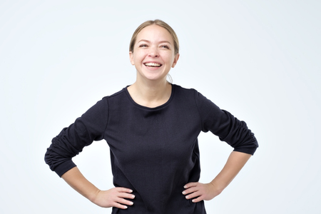Happy cheerful young woman wearing black clothes rejoicing at positive news or birthday gift, looking at camera laughing. Positive human emotion and facial expression.の写真素材