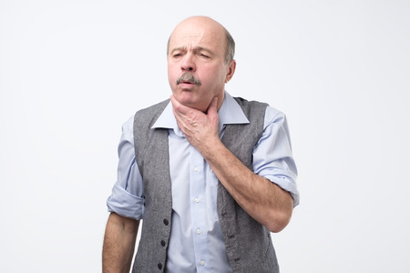 Senior man coughing being ill. Studio shoot. Flu or asthma health problem