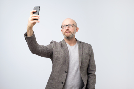 Caucasian mature man taking selfie on his phoneの写真素材