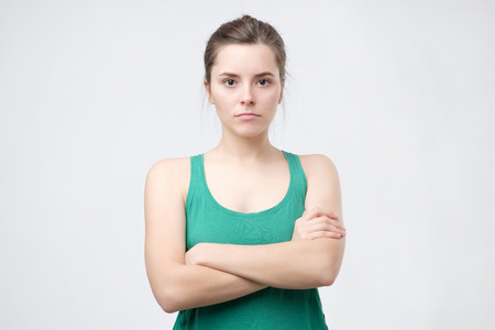 Aggravated sad woman standing crossed hands expressing her dissatisfaction and disconent. Insult teenager with placid look. People and emotions conceptの写真素材