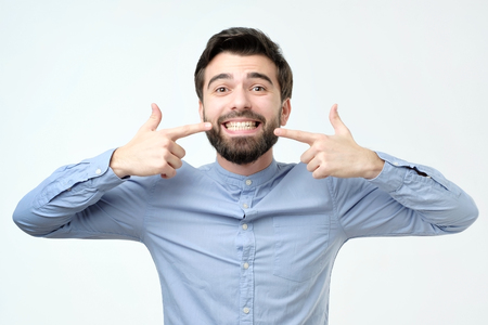 Young handsome hispanic man smiling confident showing and pointing with fingers teeth and mouth. Health concept.の写真素材