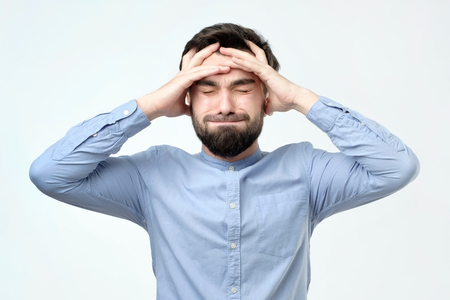 Young unhappy businessman holds his head, stress, headache and frustration concept. Negative human facial emotionの写真素材