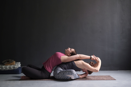 Two woman doing yoga together supta baddha konasana.